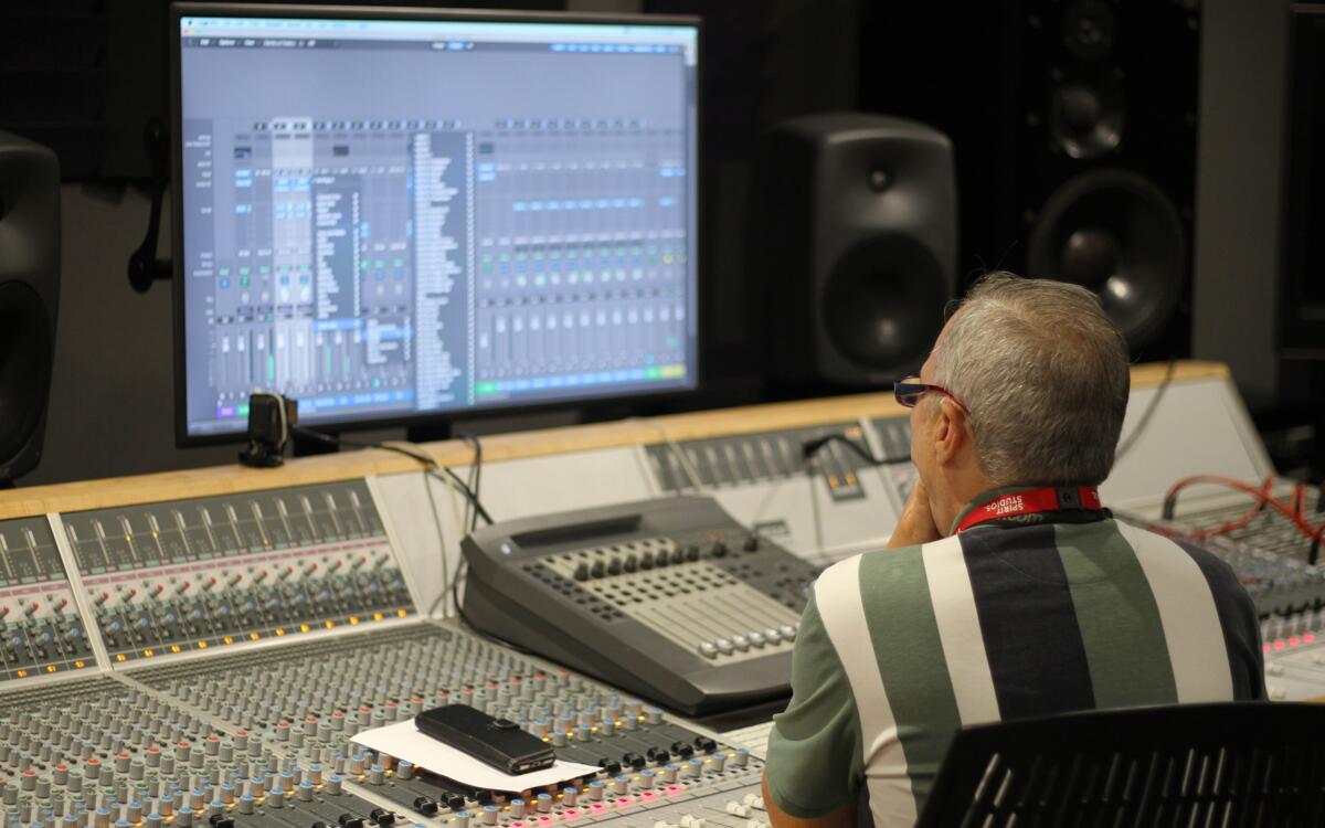 Spirit studios lecturer inside Logic Pro X looking at channel effects in front of a mixing console