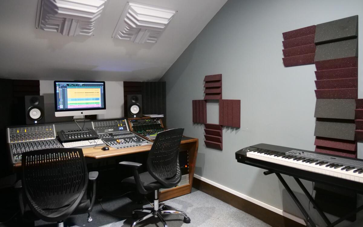 Wide shot of Audient Suite 1 showing the sound proofing methods, keyboard, midi controller and a mixing desk.