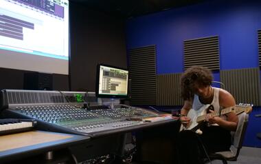 Front shot of student tracking and playing guitar in the Icon Studio