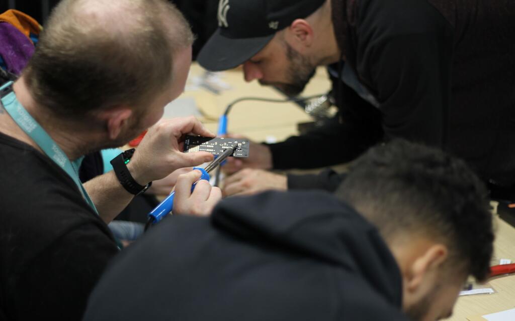 Students soldering a PCB component for a custom midi controller.