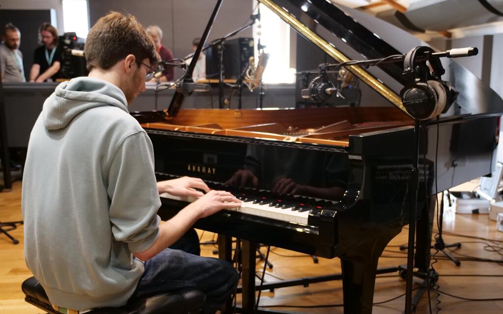 Music production student playing and recording a grand piano.