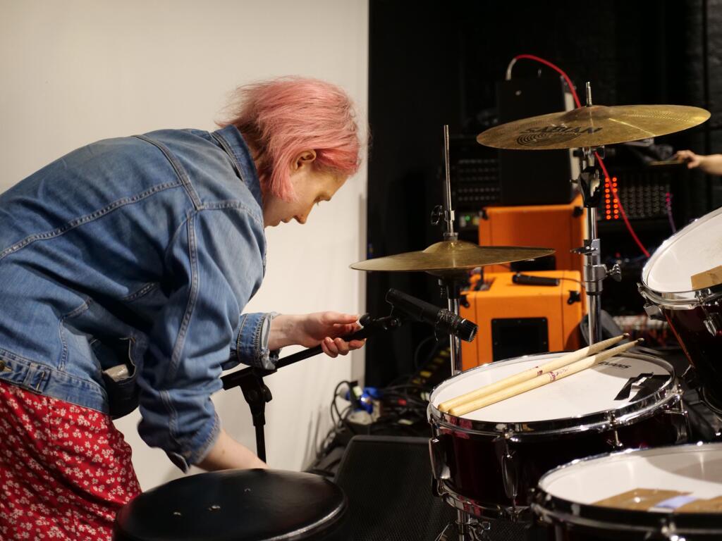 Person micing up a snare drum on stage